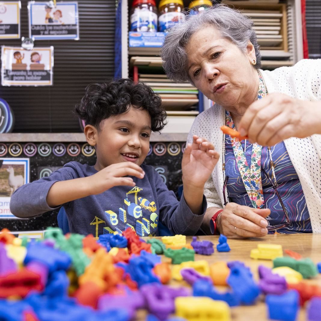  A student and staff member work with plastic learning materials